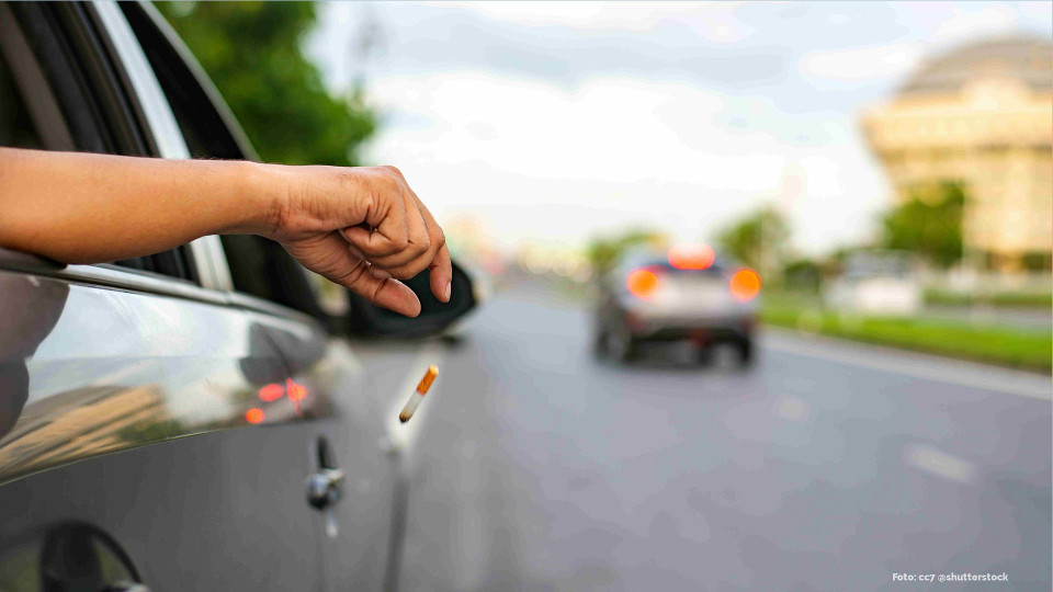 Eine Zigarettenkippe wird achtlos aus einem Autofenster geschnippst.