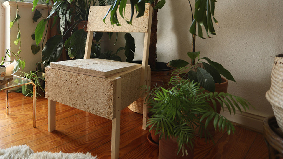 Ein Stuhl aus Hanfspanplatten in einem Zimmer. Im Hintergrund Grünpflanzen und links ein kleiner Tisch.