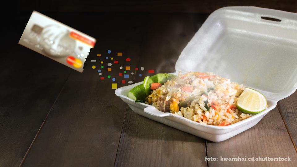 Eine Kreditkarte gibt kleine Plastikpartikel an das Essen in einem Styroporbehälter ab.