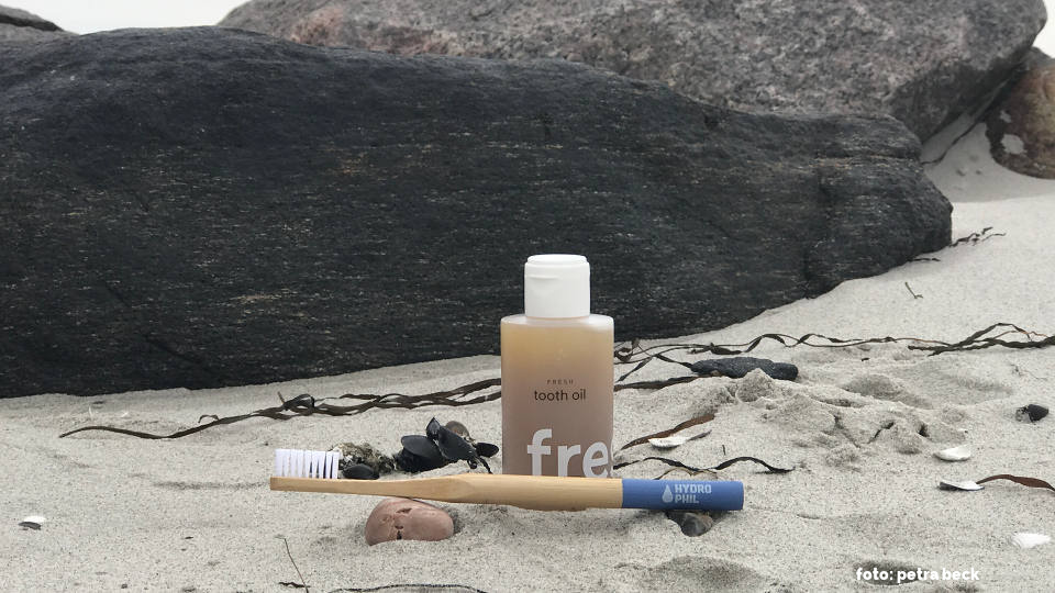 Ein Zahnöl und eine plastikfreie Zahnbürste am Strand
