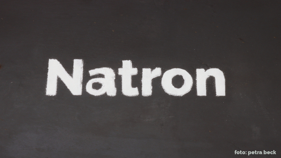 Das Wort Natron mit Pulver auf einer Schiefertafel.