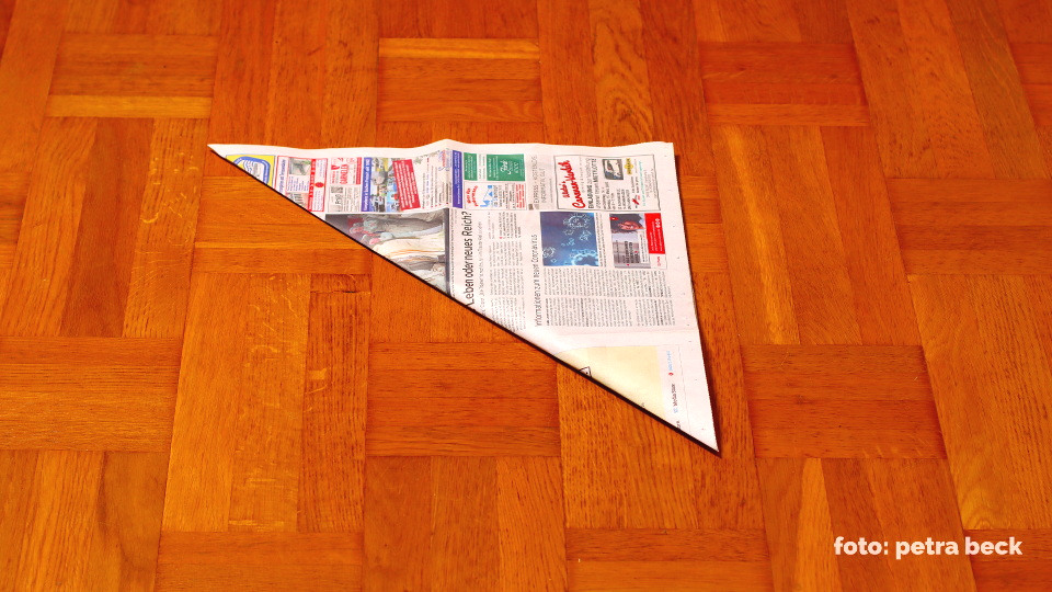 Die Zeitung wird zu einem Dreieck gefaltet.