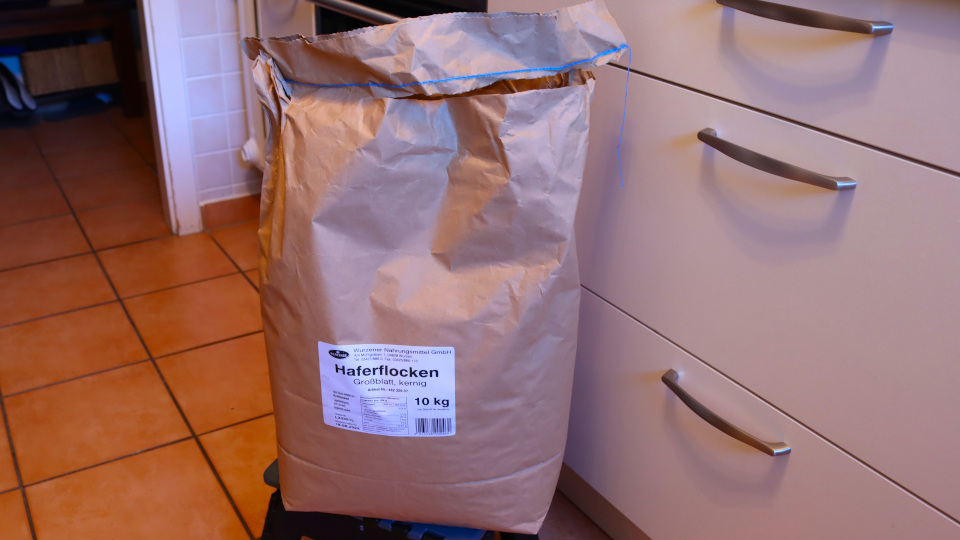 Das steht er nun der Sack aus dunklem Packpapier mit 10 kg Haferflocken in unserer Küche auf dem Boden.