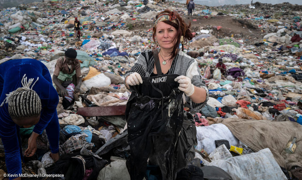 Auf dem Foto steht Viola Wohlgemuth, Expertin für Ressourcenschutz von Greenpeace, inmitten eine Halde von Altkleidern in Afrika.